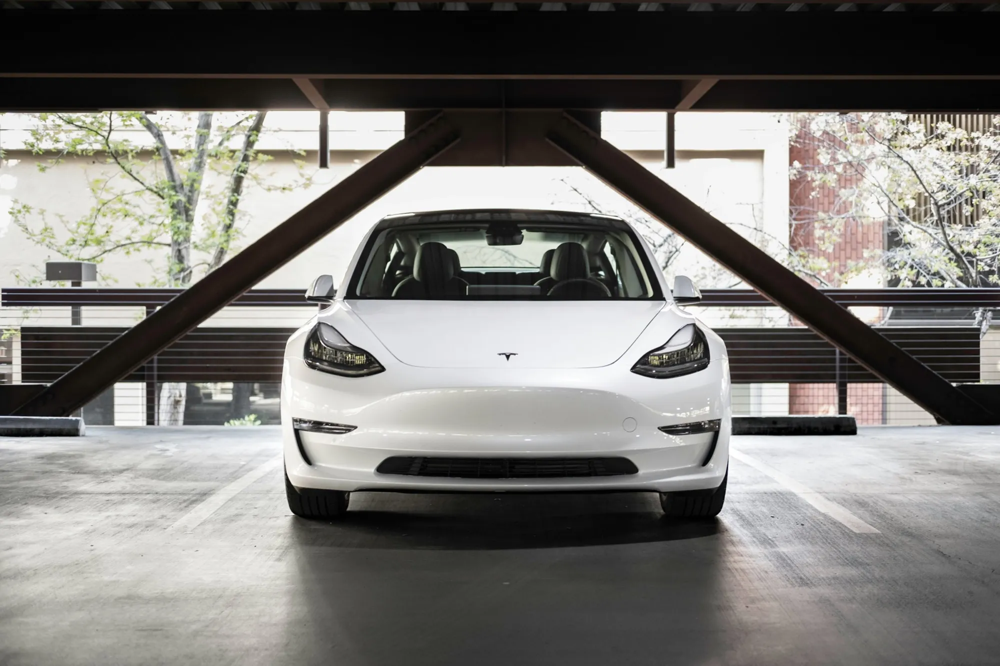 White Tesla Model 3 parked under a concrete carport